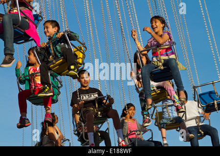 Heureux, heureux enfants virevoltant dans l'air sur un carnival ride. Banque D'Images