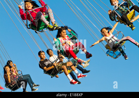 Heureux, heureux enfants virevoltant dans l'air sur un carnival ride. Banque D'Images