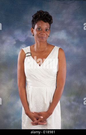 Jolie femme noire en robe blanche, debout et souriant à l'appareil photo Banque D'Images