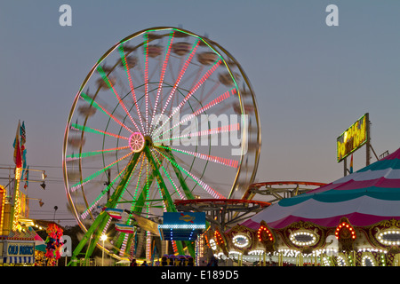 Grande roue de carnaval en mouvement avec des néons au crépuscule. Banque D'Images