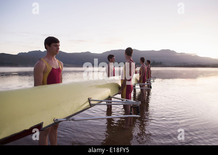 L'équipe d'aviron de godille holding dans le lac à l'aube Banque D'Images