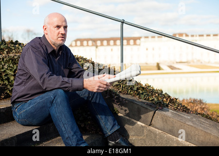 Man sitting on steps reading a newspaper Banque D'Images