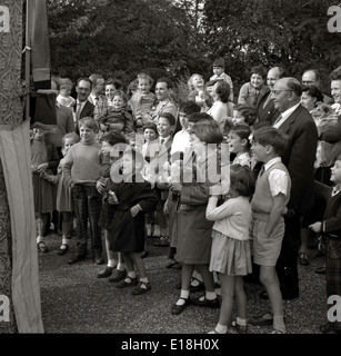 Années 1950 et un groupe de parents et d'enfants dans un parc à regarder et rire à un spectacle de marionnettes traditionnel britannique, Punch et Judy. Banque D'Images