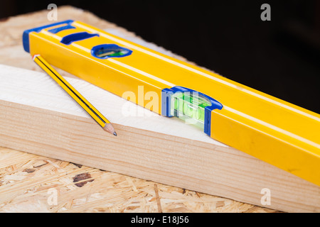 Vue rapprochée d'un jaune coloré charpentiers, règle et angle droit étendu sur des planches de bois dur avec un nouveau -12 unités as Banque D'Images