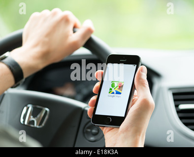 Homme dans la voiture de la planification d'un itinéraire à l'aide d'une application Google Maps sur Apple iPhone 5S. Banque D'Images