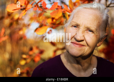 Portrait de la vieille femme en souriant. Une photo sur l'automne fond Banque D'Images