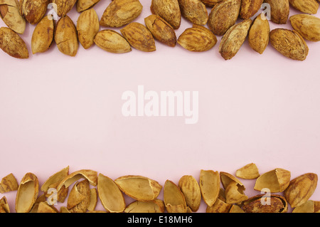 Amande avec coque placée sur le bac rose comme abstract background texture. Banque D'Images