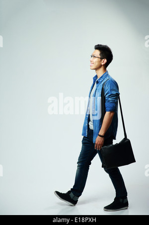 Studio shot of a young asian man walking sur fond gris Banque D'Images