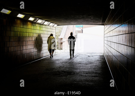 Deux personnes marchant à travers un sombre passage souterrain. Banque D'Images