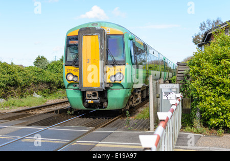 Train vert et jaune de classe 377 Electrostar Southern approchant un passage à niveau en Angleterre, au Royaume-Uni. Trains du sud. Southern Rail. Banque D'Images