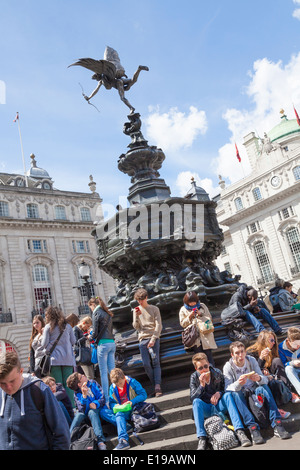 Les touristes se rassemblent pour s'asseoir autour de la statue d'Eros dans Piccadilly Circus Londres Banque D'Images
