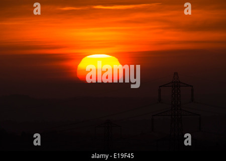 Le lever du soleil, avec des pylônes électriques à l'avant-plan. Banque D'Images