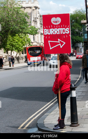 Une femme tenant un conseil Mission publicité en intérim Burrito. Banque D'Images