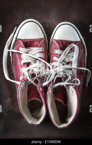 Old Red Sneakers sur le vieux cuir Banque D'Images