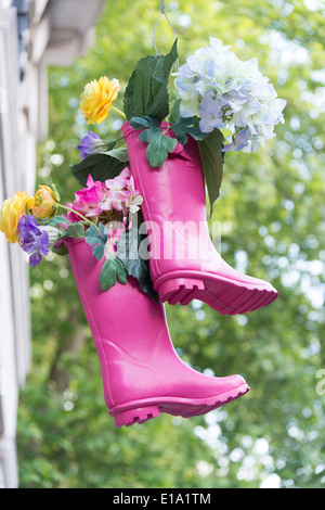 Une paire de bottes rose utilisés comme conteneurs de fleurs de raccrocher à l'extérieur d'une boutique près de la Chelsea Flower Show UK Banque D'Images