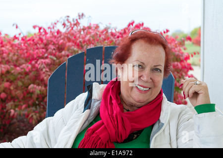 Red hair woman dehors sur une chaise bleue avec son grand sourire vêtements couleur de Noël Banque D'Images