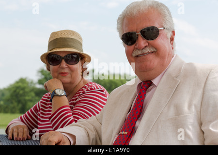 Couple retraités et détendue vous regarde avec leurs lunettes homme portant costume et cravate, femme de sa belle chemise rayée Banque D'Images