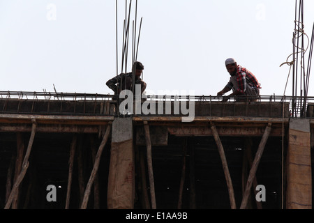 La préparation des travailleurs dans le cadre de poutres en fer portant la toiture du bâtiment. Ils préparent un maillage de plaques de métal avec les armatures. Banque D'Images