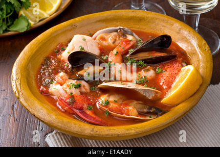 Un petit bol de ragoût de fruits de mer méditerranéen rustique au homard, crevettes, moules, palourdes, pétoncles, et le poisson blanc. Banque D'Images