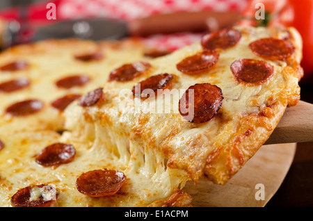 Une tranche de pizza au pepperoni, fromage fondu tirer. Banque D'Images