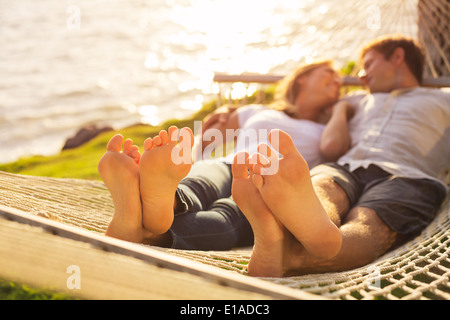 Couple romantique au coucher du soleil tropical hamac, profondeur de champ, l'accent sur pieds. Banque D'Images