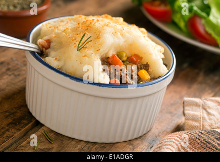 Un feu Shepherd's pie dans un ramequin sur une table rustique. Banque D'Images