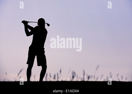 Silhouette de golfeur balancer contre le ciel clair crépuscule Banque D'Images