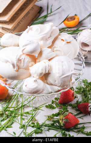 La meringue maison à l'abricot et de fraise servi sur table avec l'herbe fraîche et vintage books. Banque D'Images