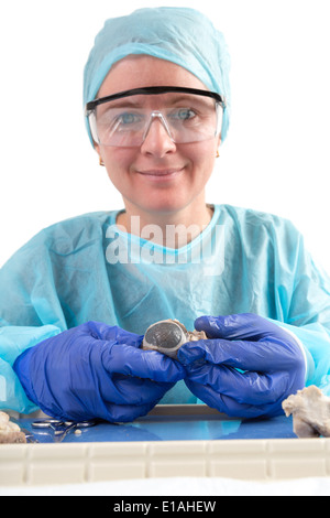 Femme technologiste médical pathologiste ou assis dans une blouse de chirurgien et le cap et le port de lunettes de protection d'un produit désinfectant sa Banque D'Images