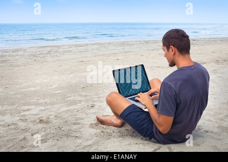 L'homme à l'aide d'ordinateur avec internet sans fil sur la plage Banque D'Images