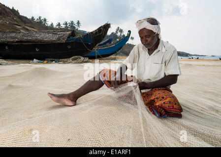 La réparation des filets de pêche pêcheur sur la plage, Kovalam, Kerala, Inde Banque D'Images