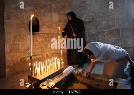 Un adorateur orthodoxe de l'est allume des bougies sur une dalle de pierre qui contient l'une des empreintes de Jésus à l'intérieur de la chapelle de l'Ascension le site traditionnellement les fidèles croient être l'endroit terrestre où Jésus s'est monté dans le ciel après sa résurrection située sur le Mont des oliviers dans le Quartier AT-Tur de Jérusalem-est Israël. Chaque année, jeudi, le 40e jour de Pâques, les chrétiens du monde entier célèbrent l'Ascension corporelle de Jésus dans le ciel. Banque D'Images