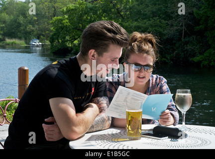 Jeune couple de déguster une boisson à l'extérieur The Swan Inn, Newby Bridge, Parc National de Lake District, Cumbria, Angleterre, Royaume-Uni Banque D'Images