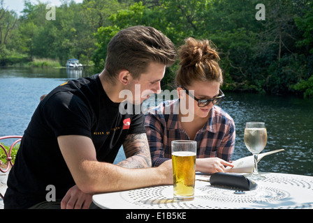 Jeune couple de déguster une boisson à l'extérieur The Swan Inn, Newby Bridge, Parc National de Lake District, Cumbria, Angleterre, Royaume-Uni Banque D'Images
