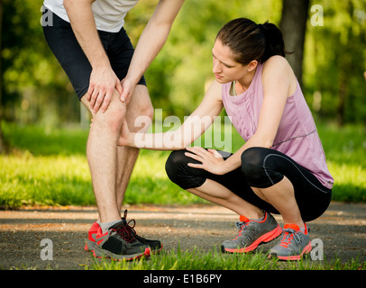 Aide à l'homme femme avec genou blessé lors de l'activité sportive Banque D'Images