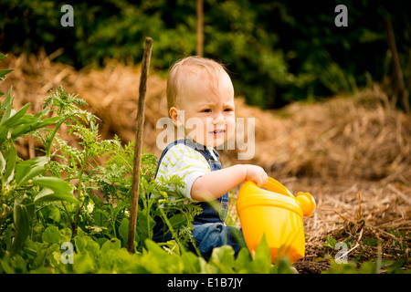 Petite fille se détend avec l'arrosoir dans le jardin Banque D'Images