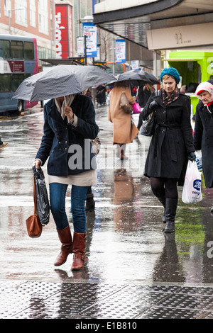 La pluie, la ville britannique. Femme avec parapluie et d'autres personnes sur le shopping et de traverser la rue sous la pluie, Nottingham, England, UK Banque D'Images