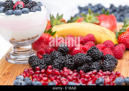La préparation d'un délicieux dessert de fruits crémeux avec des lignes colorées de fruits tropicaux propre sur le comptoir de bois, y compris les bleuets Banque D'Images