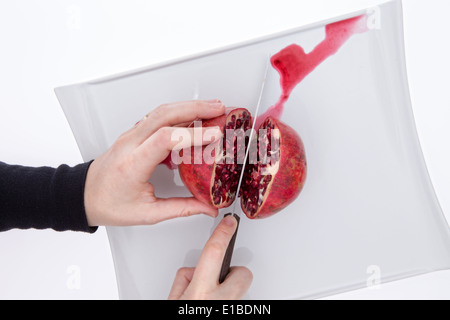 Nettoyer les mains d'un homme ou la coupe d'un chef de grenade frais entier dans la moitié de l'exposition de la pulpeuse rouge mûr ou graines arils et libération Banque D'Images