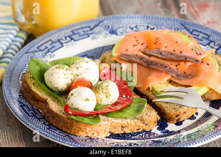 Des en-cas savoureux pique-nique en bonne santé avec le pain de blé entier garnis de saumon fumé gastronomique, avocat, fromage mozzarella, piment un Banque D'Images