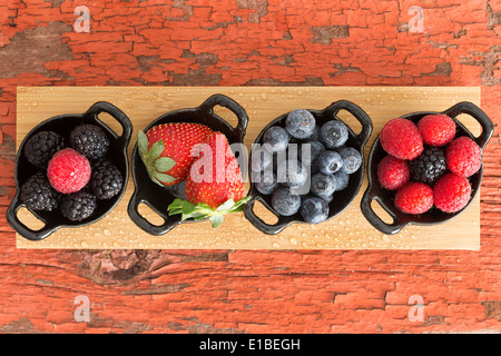 Assortiment de fruits frais mûrs automne affiché sur une planche en bois en plats individuels avec des framboises, mûres, blueber Banque D'Images