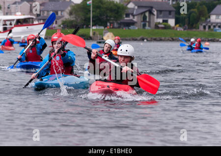 Gwynedd, Pays de Galles, Royaume-Uni. 29 mai, 2014. Les jeunes kayakistes de Gwynedd pagayer à travers Llyn Padarn, comme ils la course Lake Railway train, dans le cadre de l'Université Queen's baton relay voyage autour du Pays de Galles, avant l'ouverture des Jeux du Commonwealth à Glasgow. La mascotte des Jeux, Clyde, rode dans le train comme il a couru l'équipe de canoë sur le lac. Crédit : Michael Gibson/Alamy Live News Banque D'Images