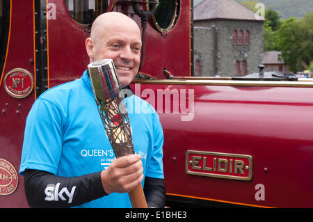 Gwynedd, Pays de Galles, Royaume-Uni. 29 mai, 2014. Monsieur Dave Brailsford (à gauche) détient le Queen's baton à côté du Llanberis Lake Railway moteur, à la fin de la course entre Llyn Padarn et kayakistes sur le train qui longe le lac. Dans le cadre de son relais voyage autour du Pays de Galles, avant l'ouverture des Jeux du Commonwealth à Glasgow, l'équipe de canoë pagayé à travers Lyn Padarn à battre le lac train dans la course. Crédit : Michael Gibson/Alamy Live News Banque D'Images