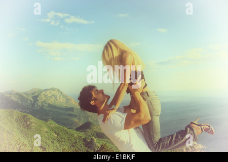 Bel homme belle femme de levage avec ciel bleu, vert des montagnes et la mer derrière Banque D'Images