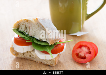 Petit-déjeuner nutritif sain composé d'un sandwich fait de pain de pommes de terre, mozzarella, tomates et feuilles fraîches de bébé Banque D'Images