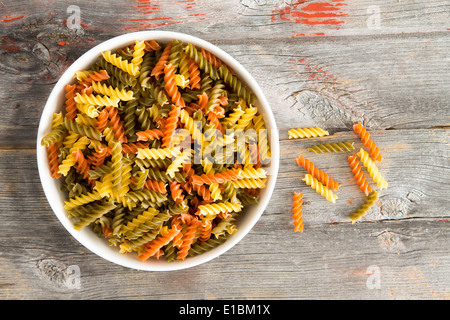 Bol coloré de tomate et les épinards crus, fusillis une Italienne les pâtes faites de spirales Banque D'Images