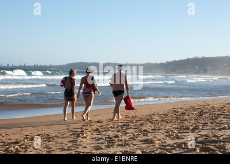 Trois personnes marchant le long de la rive nord à Narrabeen beach, Sydney. Banque D'Images