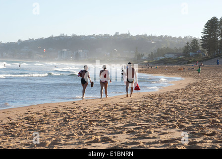 Trois personnes marchant le long de la rive nord à Narrabeen beach, Sydney. Banque D'Images