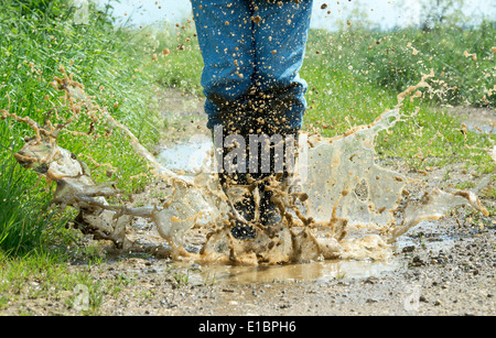L'homme en bottes de sauter dans une flaque d'eau sur une piste dans la campagne anglaise Banque D'Images