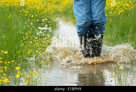 Dans l'homme bottes wellington aux projections d'eau dans un champ inondé. L'Angleterre Banque D'Images